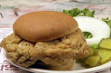 Gebakken kalfshersenen in een hamburgerbroodje met zure augurk, verse uiringen en salade